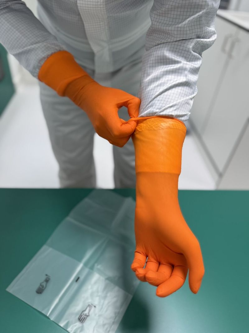 Reinraumhandschuh wird über den Ärmel der Reinraumkleidung gezogen